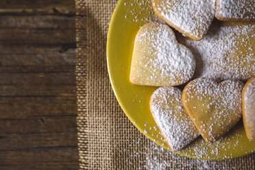 Heart-shaped shortbreads sprinkled with icing sugar on yellow plate - GIOF01776