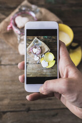 Woman taking a photo of shortbreads and cup of milk with her smartphone, close-up - GIOF01810