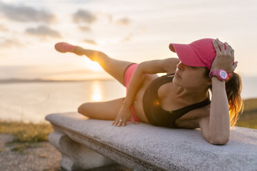 Junge Frau beim Krafttraining auf einer Bank am Meer - MGOF02892