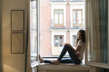 Frau auf dem Fensterbrett sitzend bei offenem Fenster - KKAF00377