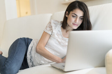 Porträt einer Frau auf einer Couch mit Laptop - KKAF00387