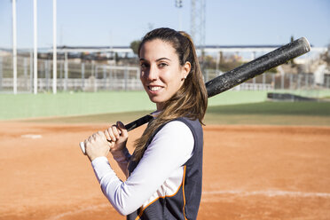 Portrait of smiling female baseball player with a baseball bat - ABZF01892