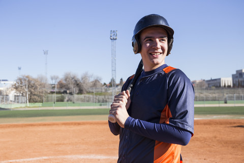 Lächelnder Baseballspieler, der einen Baseballschläger hält, lizenzfreies Stockfoto