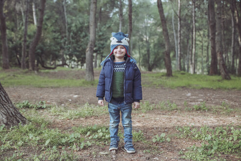 Porträt eines lächelnden Jungen mit Wollmütze im Wald - RTBF00624