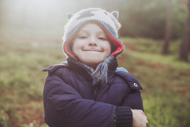 Porträt eines grinsenden Jungen mit Wollmütze im Wald - RTBF00647