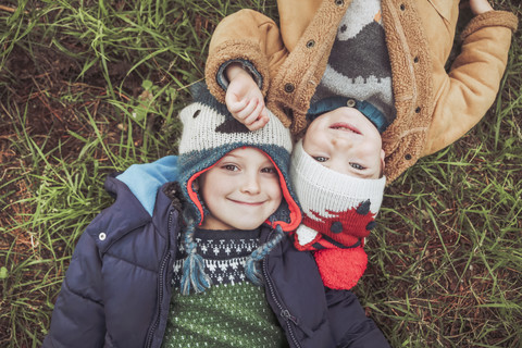 Zwei Jungen mit Wollmützen liegen im Gras, lizenzfreies Stockfoto