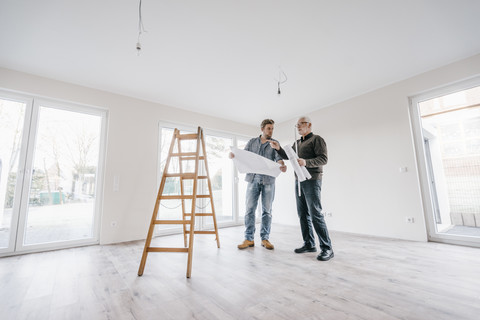 Architekt prüft Bauplan mit Bauherrn des neuen Hauses, lizenzfreies Stockfoto