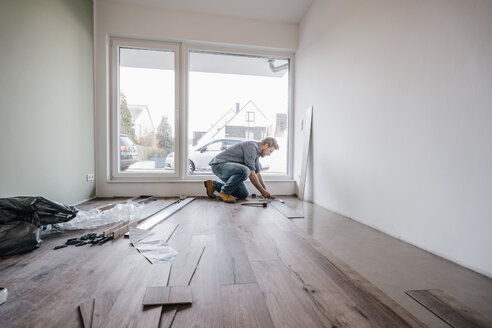 Mature man fitting flooring in new home - JOSF00491