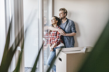 Happy couple standing at window of their new home - JOSF00512