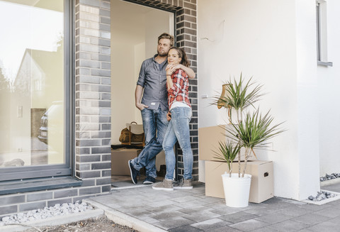 Ein glückliches Paar steht in der Tür seines neuen Hauses, lizenzfreies Stockfoto