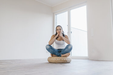 Frau sitzt auf einem Kissen in ihrer neuen Wohnung - JOSF00548