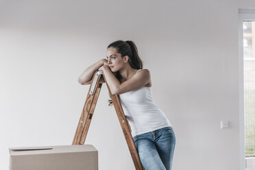 Mature woman standing in her new home, leaning on ladder - JOSF00560