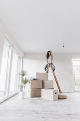 Mature woman sitting on ladder in her new home - JOSF00561