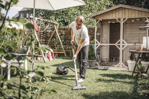 Mann säubert Rasen im Garten - JOSF00566