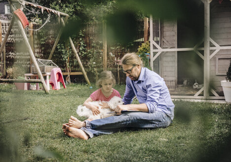 Vater liest mit Tochter im Garten ein Buch - JOSF00573