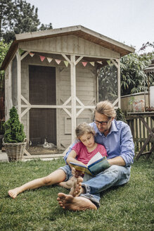 Vater liest mit Tochter im Garten ein Buch - JOSF00574