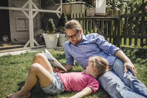 Vater liest mit Tochter im Garten ein Buch - JOSF00575