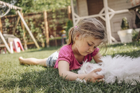 Mädchen liegend im Garten mit Hund - JOSF00577