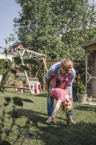 Father playing with daughter in garden stock photo