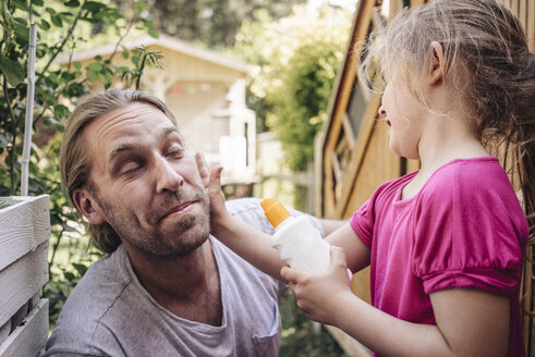 Tochter trägt Sonnenschutzmittel auf das Gesicht des Vaters im Garten auf - JOSF00585