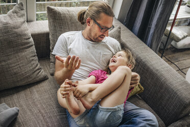 Father playing with daughter on sofa - JOSF00589