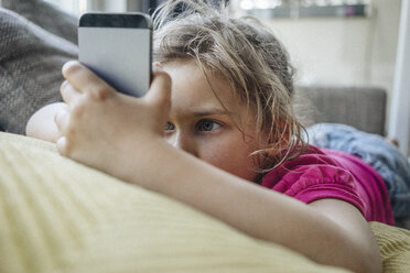 Girl lying on couch using smartphone - JOSF00592