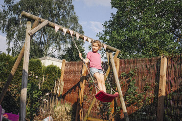 Girl standing on swing in garden - JOSF00595