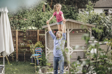 Father carrying daughter on shoulders in garden - JOSF00609