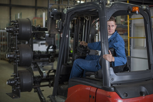 Factory working driving a fork lift in warehouse - ZEF12759