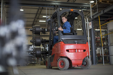 Factory working driving a fork lift in warehouse - ZEF12760