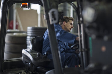 Factory working driving a fork lift in warehouse - ZEF12773