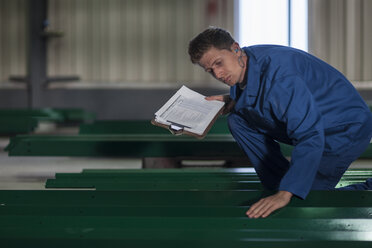 Factory worker in truck manufacture inspecting steel parts - ZEF12782