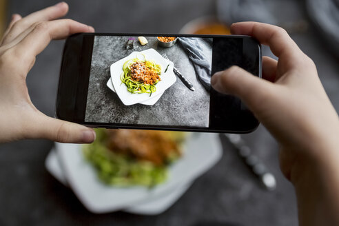 Mädchen fotografiert Nudeln mit vegetarischer Bolognesesauce mit ihrem Smartphone, Nahaufnahme - SARF03176