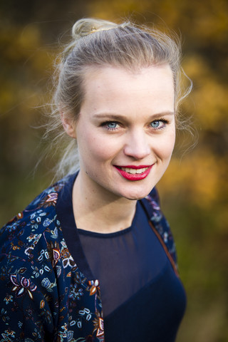 Porträt einer lächelnden jungen Frau im Herbst, lizenzfreies Stockfoto