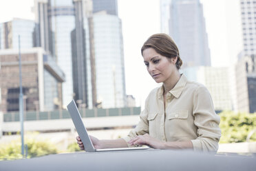 Businesswoman using laptop outdoors - WESTF22588