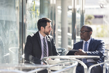 Two businessmen at outdoor cafe with tablet - WESTF22597