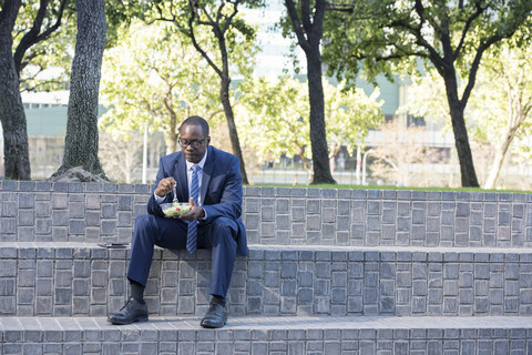 Geschäftsmann sitzt auf einer Außentreppe beim Mittagessen, lizenzfreies Stockfoto