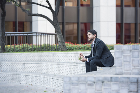 Geschäftsmann sitzt auf einer Außentreppe beim Mittagessen, lizenzfreies Stockfoto