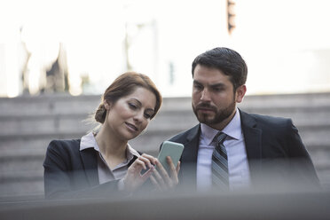Businesswoman sharing cell phone with colleague - WESTF22647