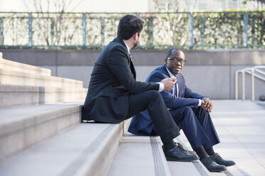 Two businessmen sitting on stairs talking - WESTF22665