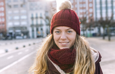 Portrait of smiling teenage girl wearing woolly hat and scarf - MGOF02902