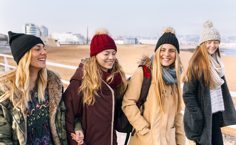 Vier Freunde gehen in der Nähe des Strandes spazieren, lizenzfreies Stockfoto