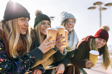 Vier Freunde stoßen im Winter mit Kaffee zum Mitnehmen an - MGOF02946
