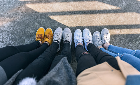Legs of four friends standing side by side stock photo