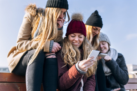 Vier Freunde schauen auf Handys, lizenzfreies Stockfoto