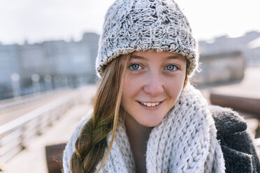 Portrait of smiling teenage girl wearing woolly hat and scarf - MGOF02956