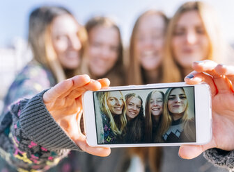 Gruppenbild von vier Freunden auf dem Display eines Smartphones, Nahaufnahme - MGOF02966