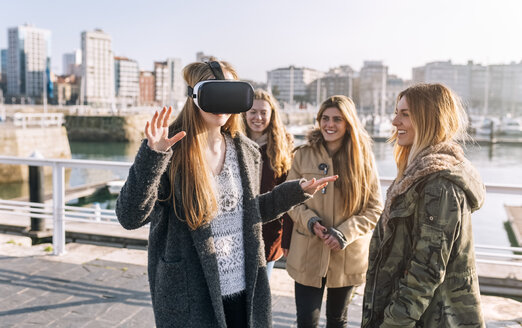 Teenager-Mädchen trägt eine VR-Brille, während ihre Freunde sie beobachten - MGOF02970