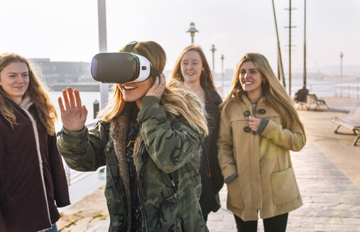 Teenager-Mädchen trägt eine VR-Brille, während ihre Freunde sie beobachten - MGOF02974