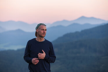 Austria, Mondsee, Mondseeberg, portrait of man wearing a basecap at dusk - WVF00847